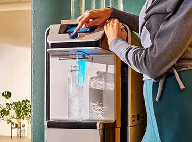 Person filling glass of water from water cooler