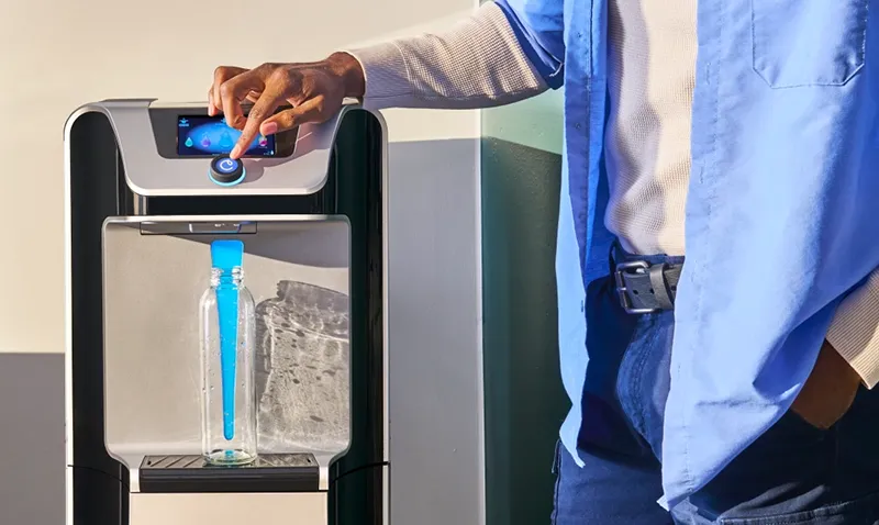 Employee getting water from a water cooler in a workplace.