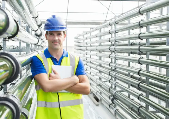 man in work uniform standing by water pipes