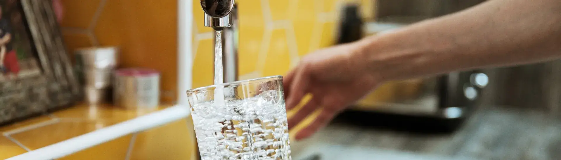 Person fulling a glass of water from the tap