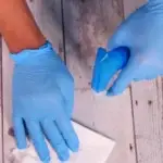 Person with blue gloves on spraying the floor and wiping