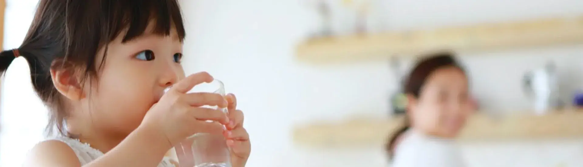 small girl drinking a glass of water