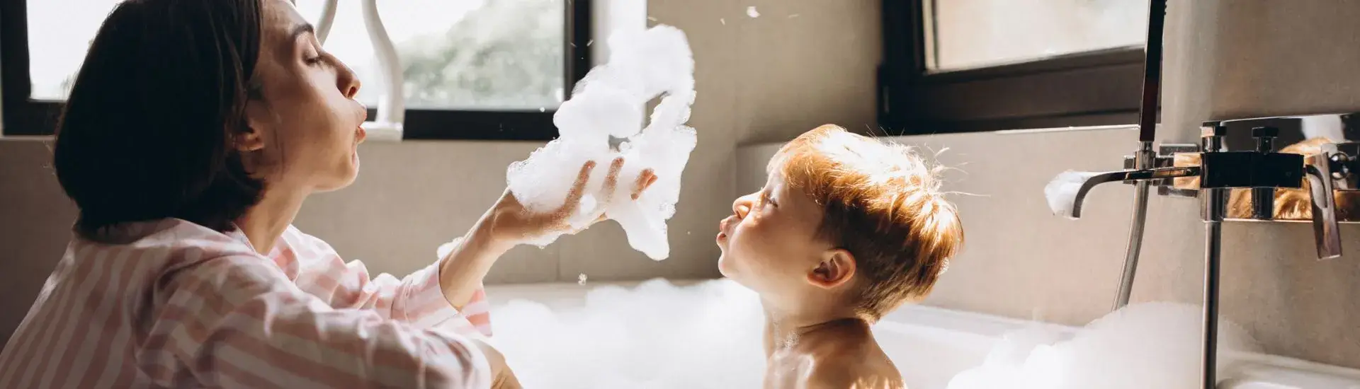 mother bathing son in bubble bath